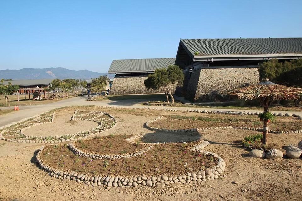 百步蛇廣場：地上用石頭排出蛇形圖案，後方是石牆、綠色屋頂的建築。
